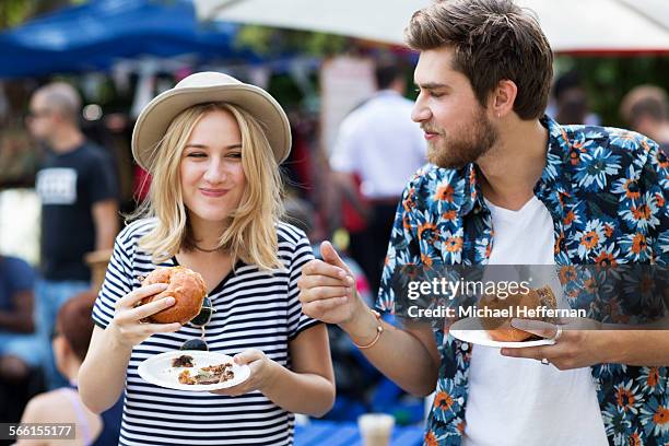 couple eating burgers at food market - street food fotografías e imágenes de stock