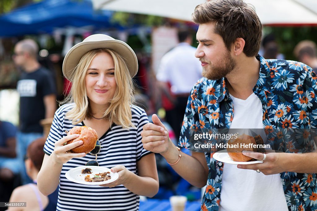 Couple eating burgers at food market