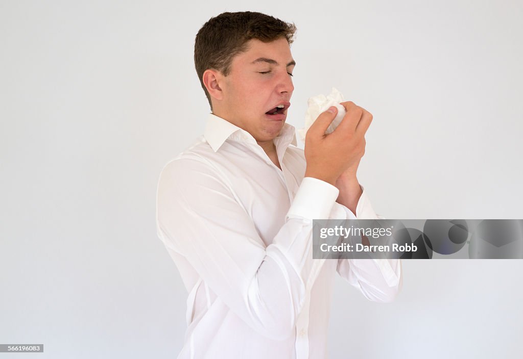 Young businessman about to sneeze into a tissue