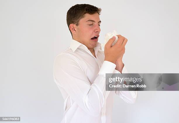 young businessman about to sneeze into a tissue - sneezing stockfoto's en -beelden