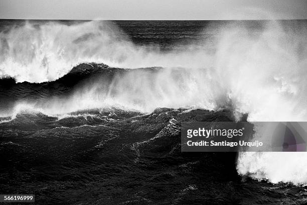 big wave crashing with spray blowing up on the air - black and white imagens e fotografias de stock