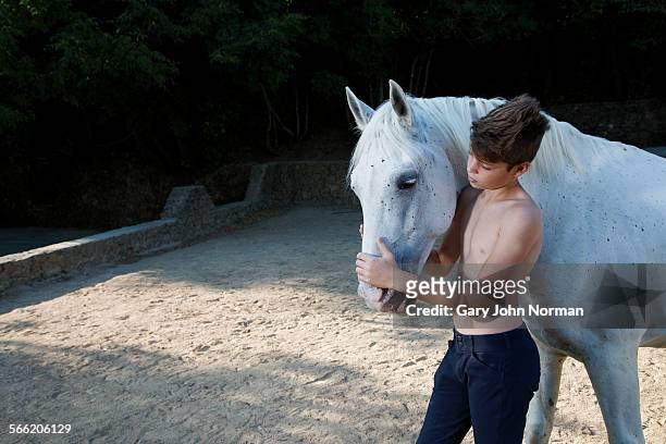 boy standing close to his horse - caballo blanco fotografías e imágenes de stock