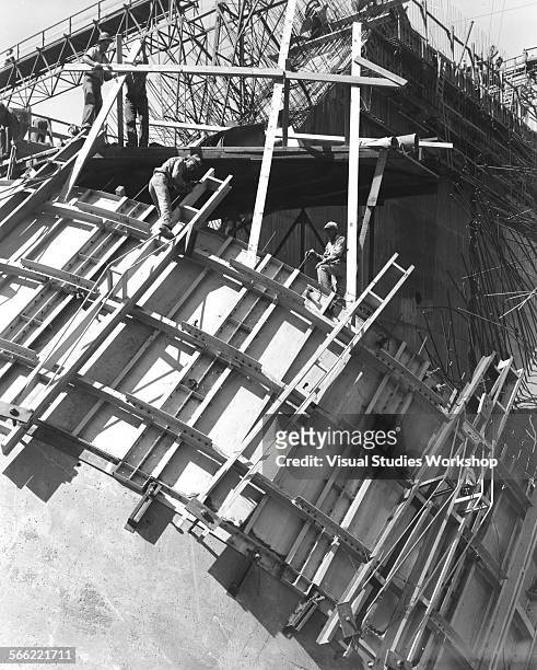 Agile workmen are shown laying the frames for concrete on one of the Bartlett Dam's ten arches, under construction on the Verde River, 50 miles north...