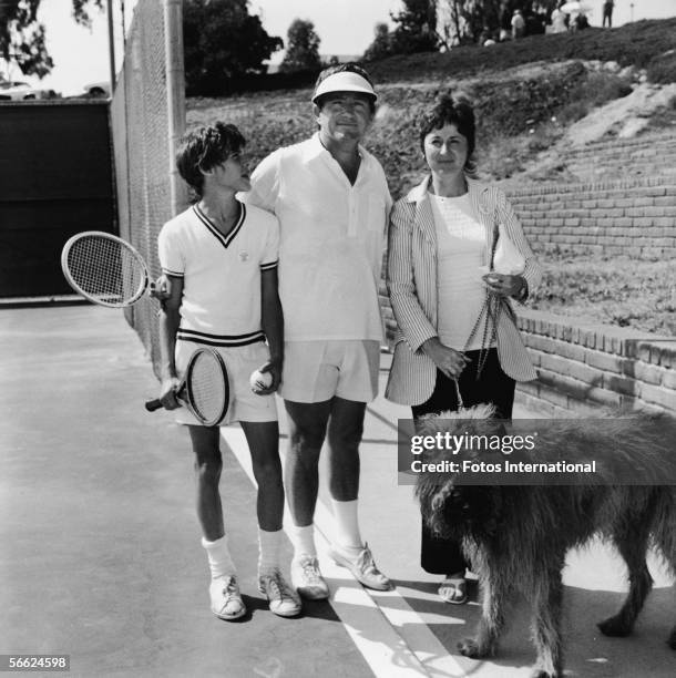 American singer, actor, talk show host, and empresario Merv Griffin is flanked by his son Tony, wife, future internet quiz entrepreneur Julann, and...