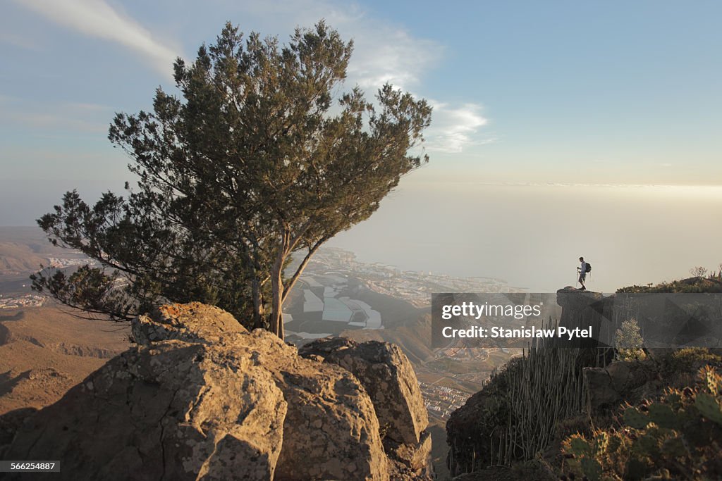 Man standing on rock above city and ocean