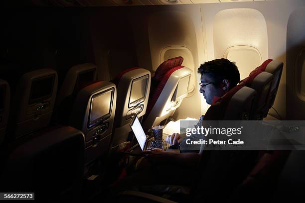 man looking at laptop, on an aircraft. - flugzeugsitz stock-fotos und bilder