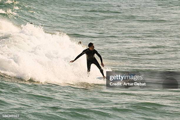 Surfer riding a wave in the Mediterranean Sea during the sunset light. Vilassar de Mar, Catalonia, Europe. 12th June of 2015.