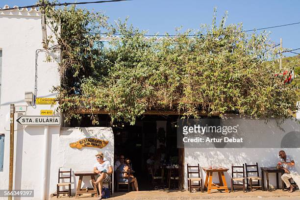 People on the bar terrace with summer light on the white architecture of the Ibiza island.