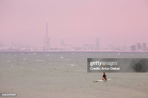 Surfer waiting for the waves in the Barcelona shoreline with the city views. Masnou, Catalonia, Europe.