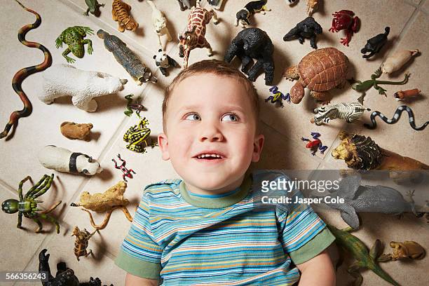 caucasian boy surrounded near toy animals - circondare foto e immagini stock