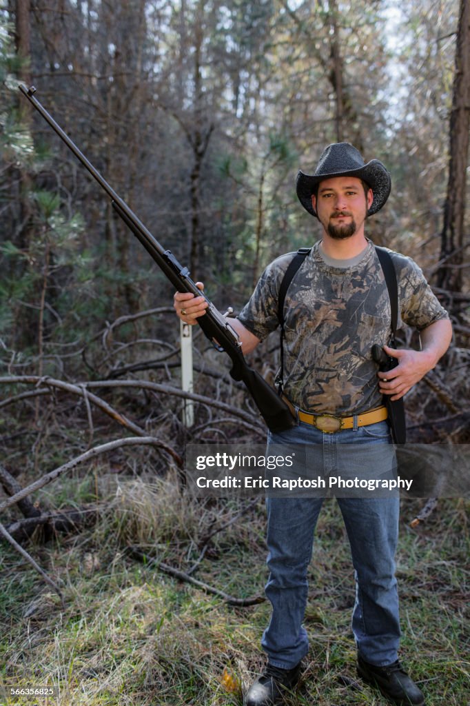 Caucasian hunter holding gun in forest