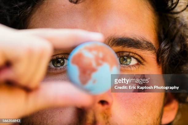 close up of hispanic man holding miniature globe - responsibility stock-fotos und bilder