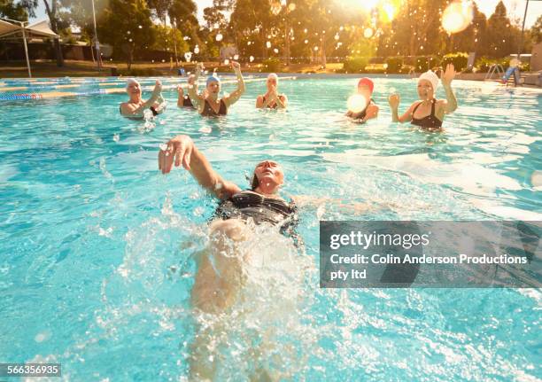 older caucasian women playing in swimming pool - buitenbad stockfoto's en -beelden