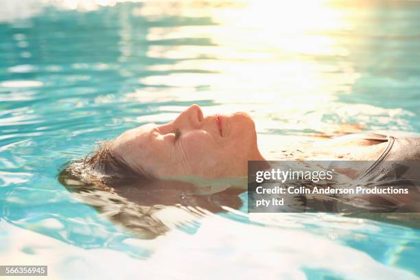 older caucasian woman floating in pool - bath relaxation stock pictures, royalty-free photos & images