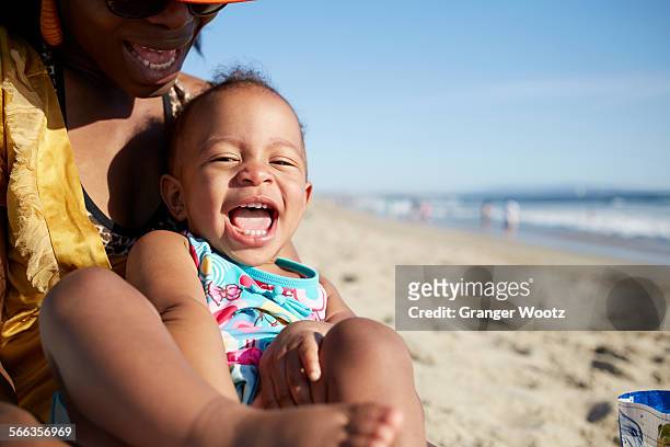 close up of mother and daughter playing on beach - baby in sunglass stockfoto's en -beelden