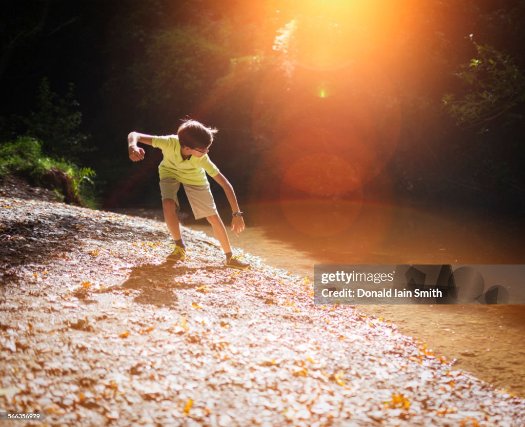 Mixed race boy skipping stones in stream