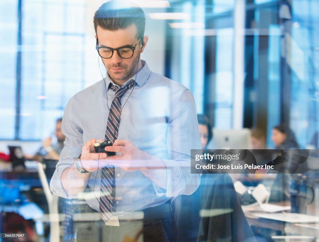 Caucasian businessman listening to mp3 player in office