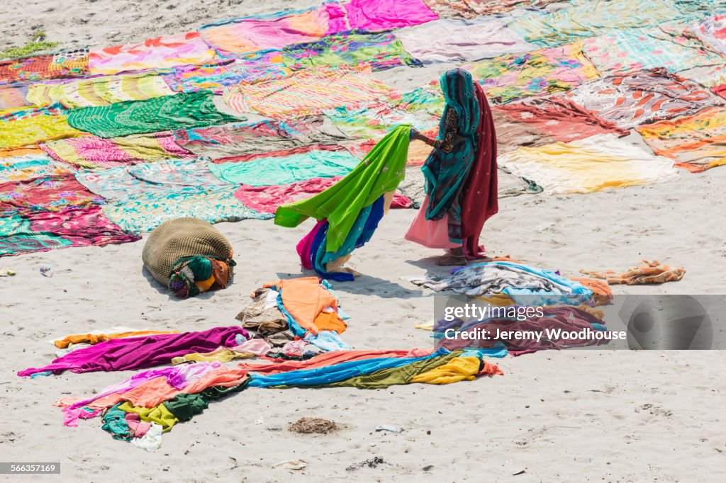 High angle view of woman drying saris on flat ground