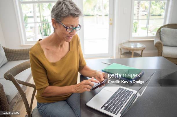 woman using cell phone and laptop in living room - reading glasses top view stock pictures, royalty-free photos & images