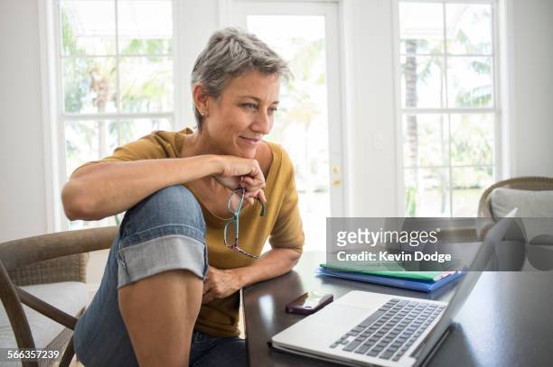 woman using laptop in living room - mujer 50 años fotografías e imágenes de stock