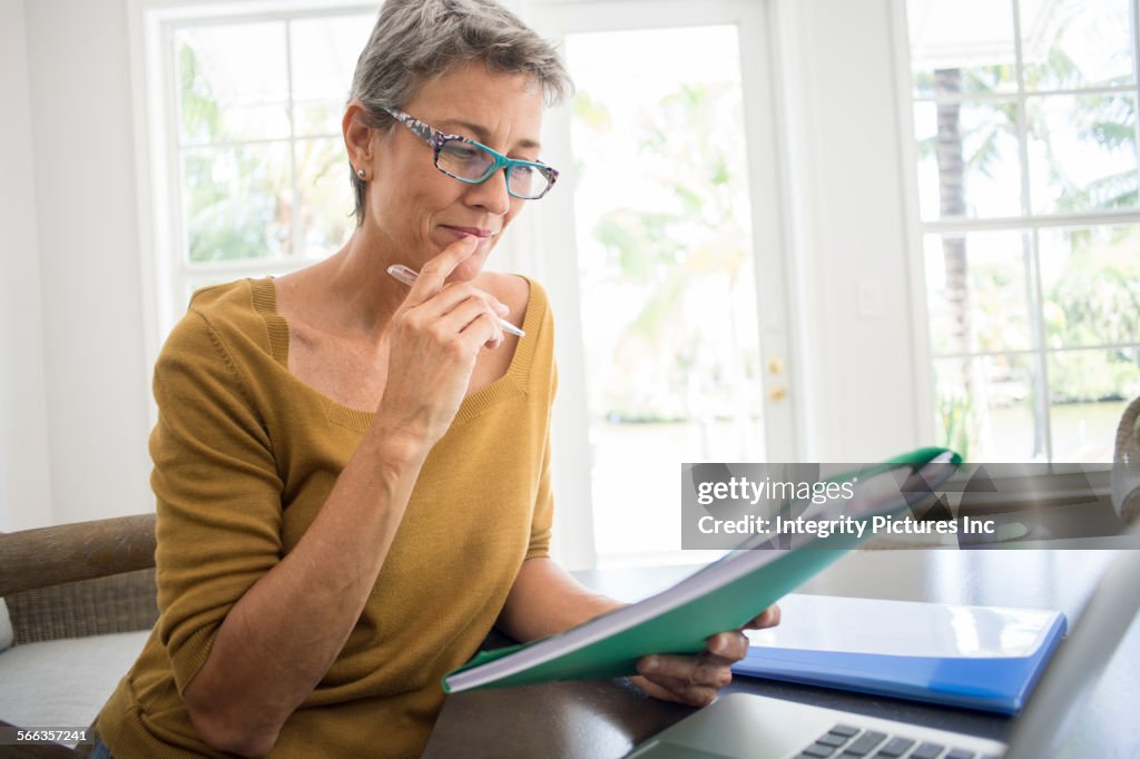 Woman reading folder at desk in living room