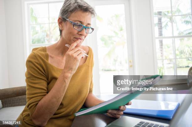 woman reading folder at desk in living room - pensionamento foto e immagini stock