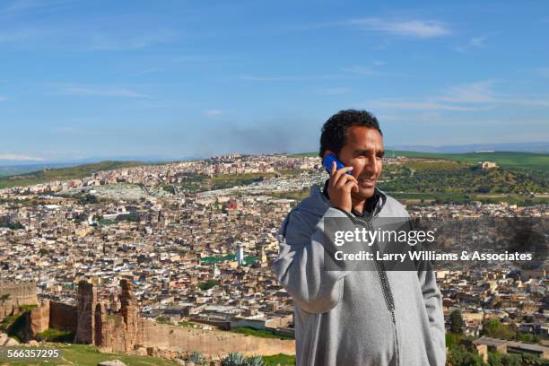 man talking on cell phone over fes cityscape, fes-boulemane, morocco - fes morocco stock pictures, royalty-free photos & images