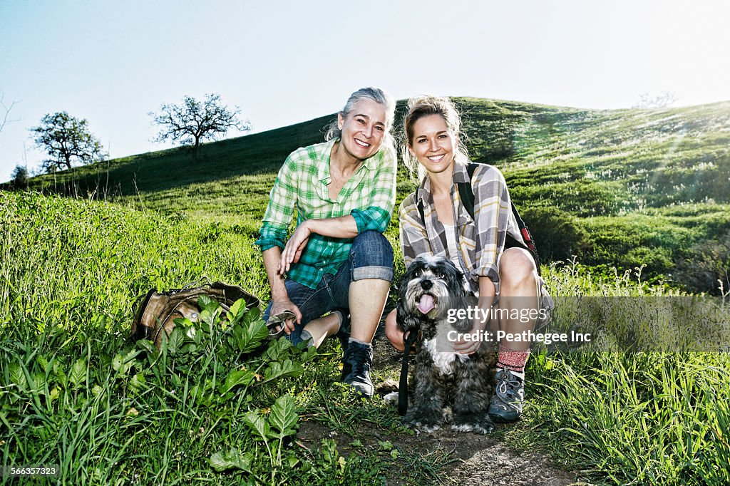 Caucasian mother and daughter walking dogs on grassy hillside