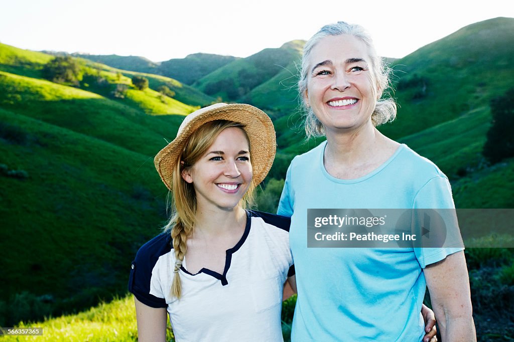 Caucasian mother and daughter smiling on rural hilltop