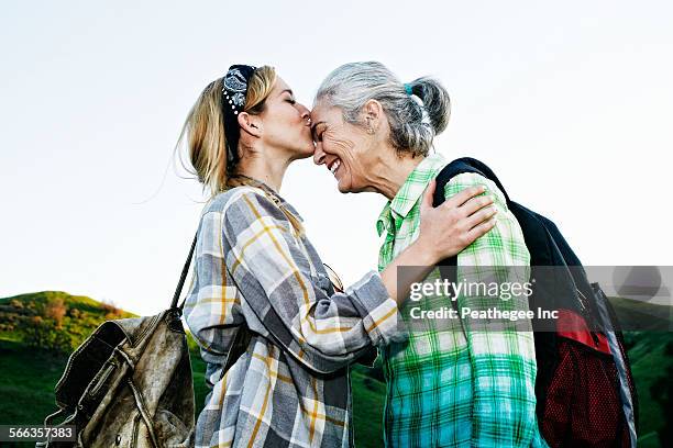 caucasian daughter kissing mother on rural hilltop - forehead stock-fotos und bilder