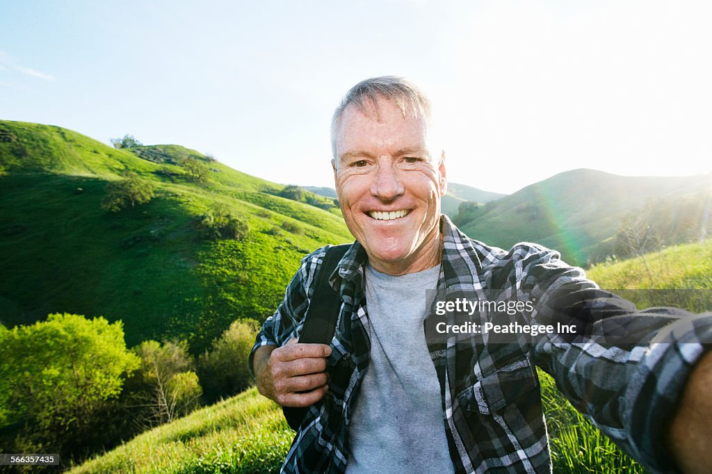 Older Caucasian man taking selfie on rural hilltop