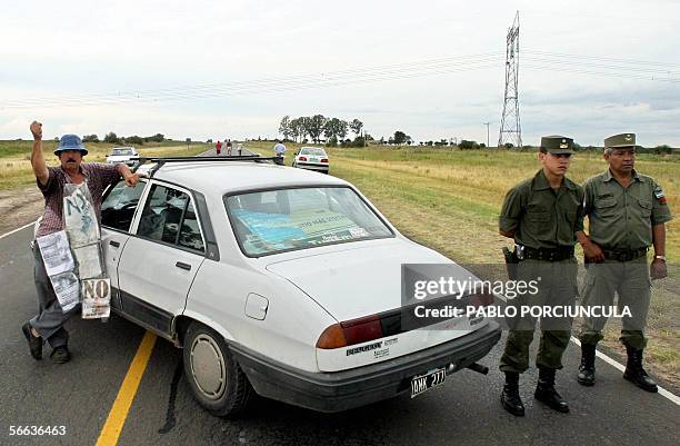 Un ambientalista argentino levanta su puno cuando saluda, junto a miembros de la Gendarmeria que controlan un corte de ruta a unos 25 km de la...