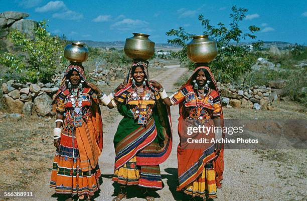 Three country women carrying metal pots on their heads in India, circa 1965.
