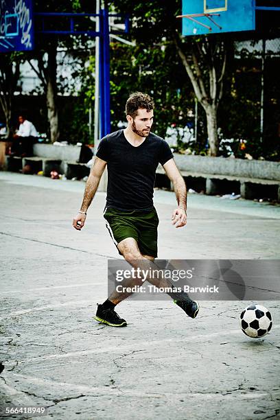 male soccer player passing ball during game - fussball pass stock-fotos und bilder