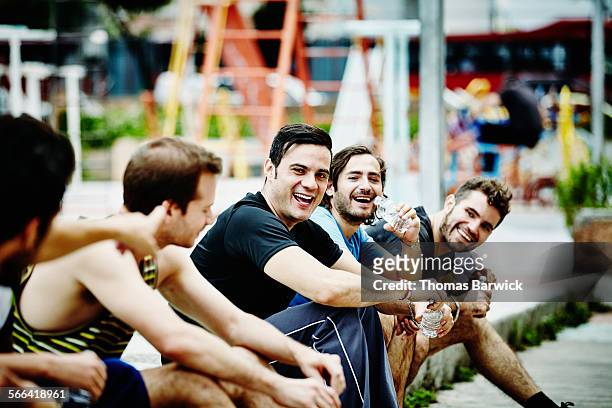 laughing friends sitting together in city park - five friends unity stock pictures, royalty-free photos & images