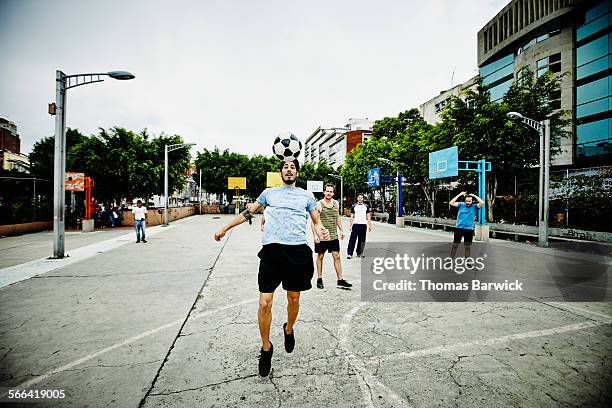 soccer player heading ball during pick up game - coordinated effort stock pictures, royalty-free photos & images