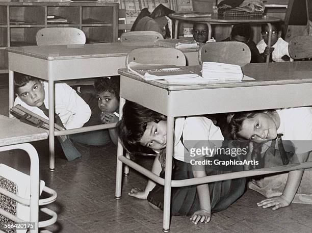 Students at a Brooklyn middle school have a 'duck and cover' practice drill in preparation for a nuclear attack; silver print, 1962. From the New...