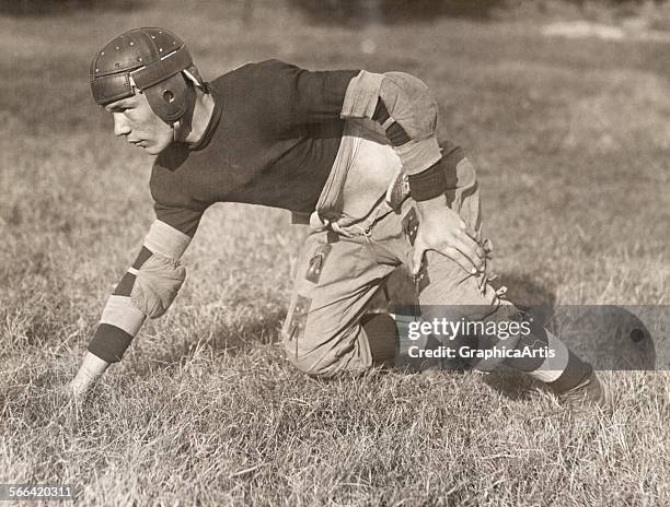 Vintage 1920s American football player in the three-point stance of an offensive guard; toned photograph, 1920 - 25.