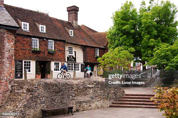 Two cyclists riding past the 14th Century Parrot pub in Canterbury.