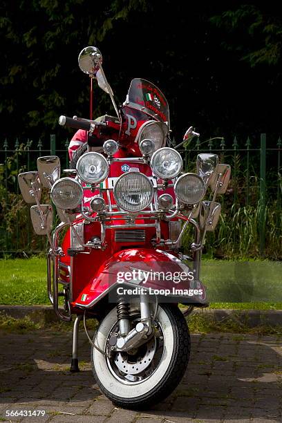 Red scooter with many lights and mirrors in the style of a mod scooter from the 1960's.