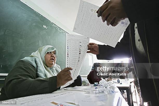 An election worker explains how to vote, to a member of Palestinian security forces as he votes for the Palestinian legislative candidates in an...