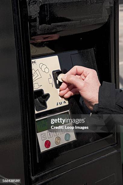 Man putting a coin into a car park meter.