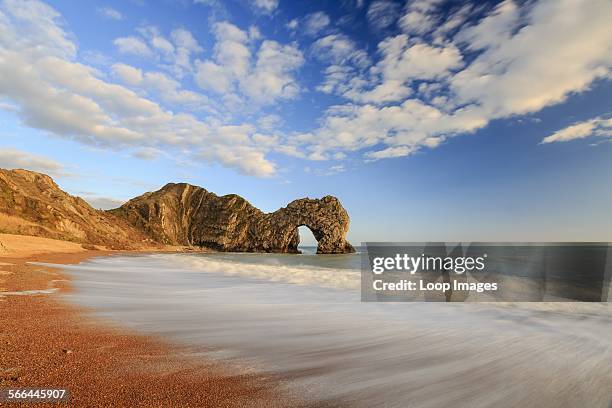 The natural Rock Arch of Durdle Door lit by the evening sun.