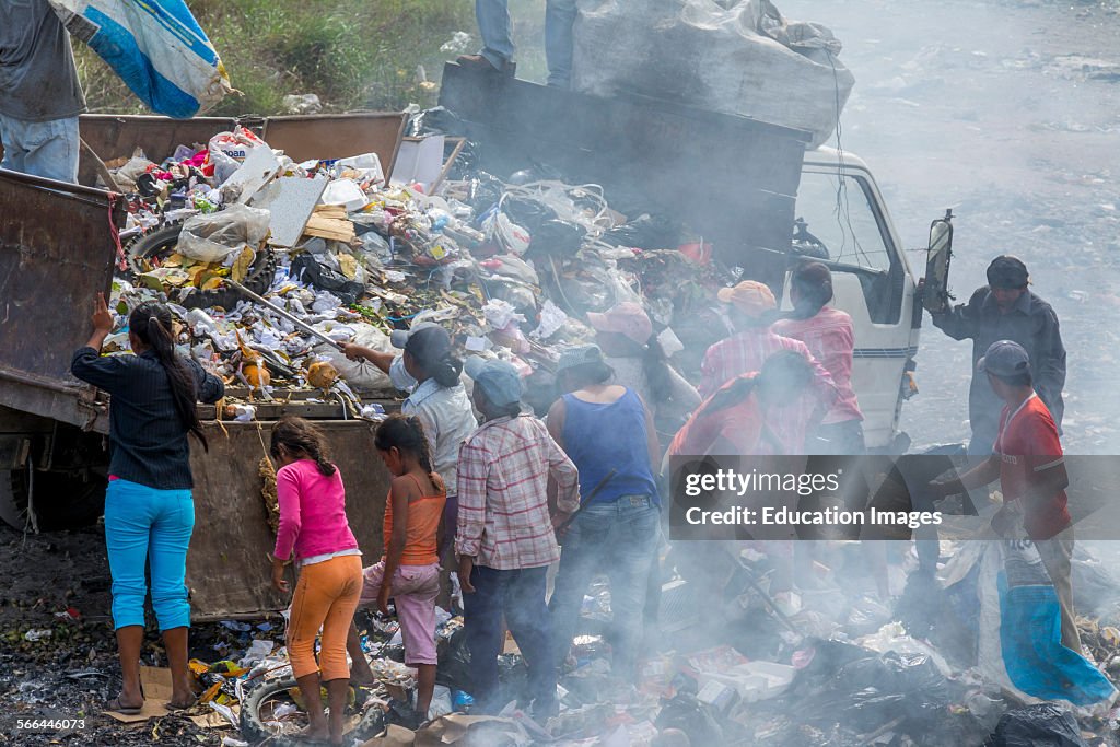 Poor people unloading and sorting recyclables from a garbage truck