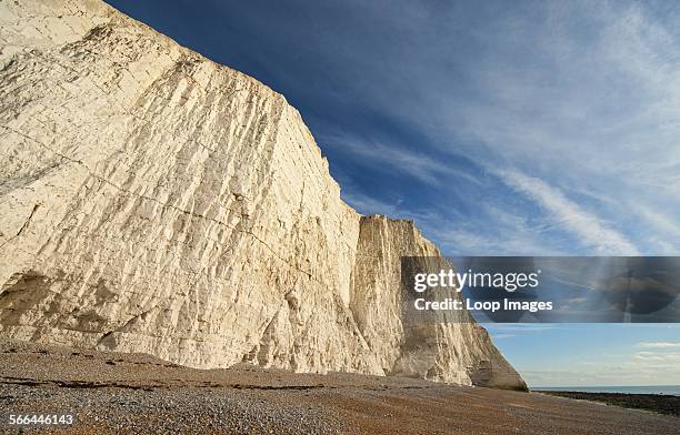 Shingle beach under vertical stratified chalk sea cliffs at Cuckmere Haven.