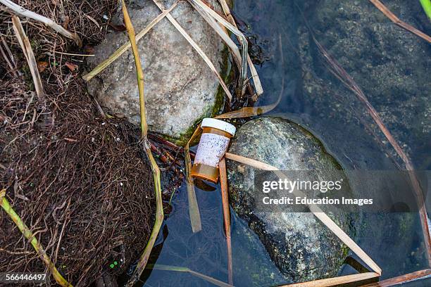 Discarded prescription bottle in the Los Angeles River after the first rain of the season, Glendale Narrows, Los Angeles, California.