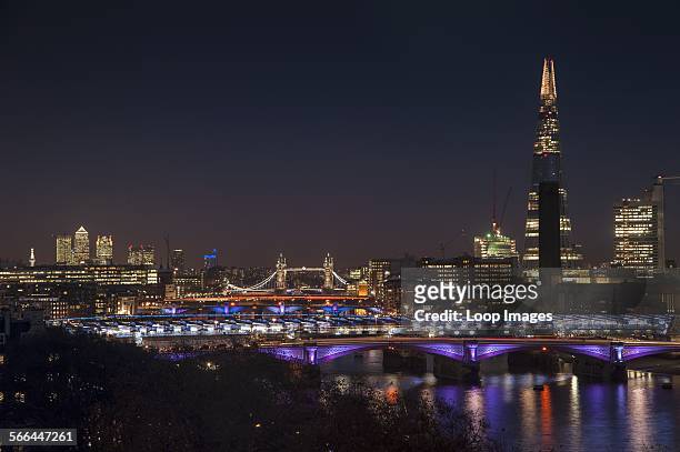 The London skyline at night including The Shard with Tower Bridge and Canary Wharf.
