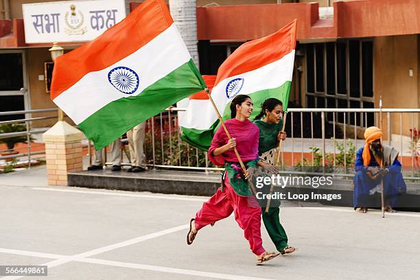 Two young women running waving the Indian Flag at the India and Pakistan border changing of the guards ceremony.