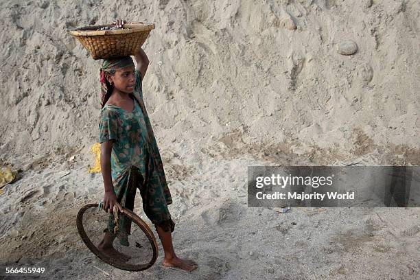 Young girl carries stones and pebbles collected from a stone quarry, on the bank of Dauki river, Sylhet, Bangladesh. January 18, 2010.