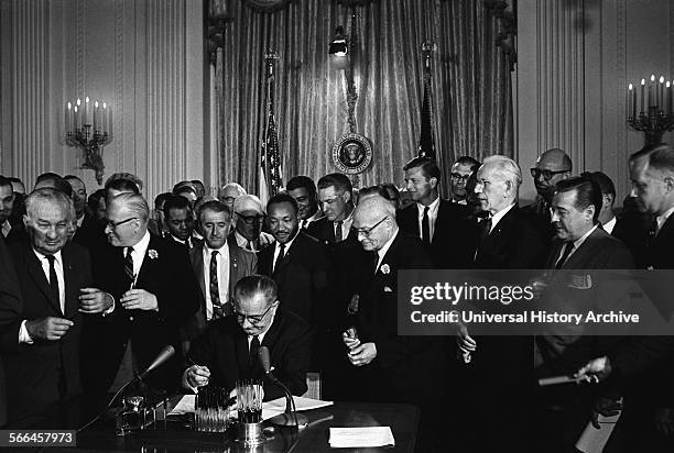 Photograph of Lyndon Johnson, President of the United States of America, signing Civil Rights Act. Behind Johnson is Martin Luther King Jnr. Dated...